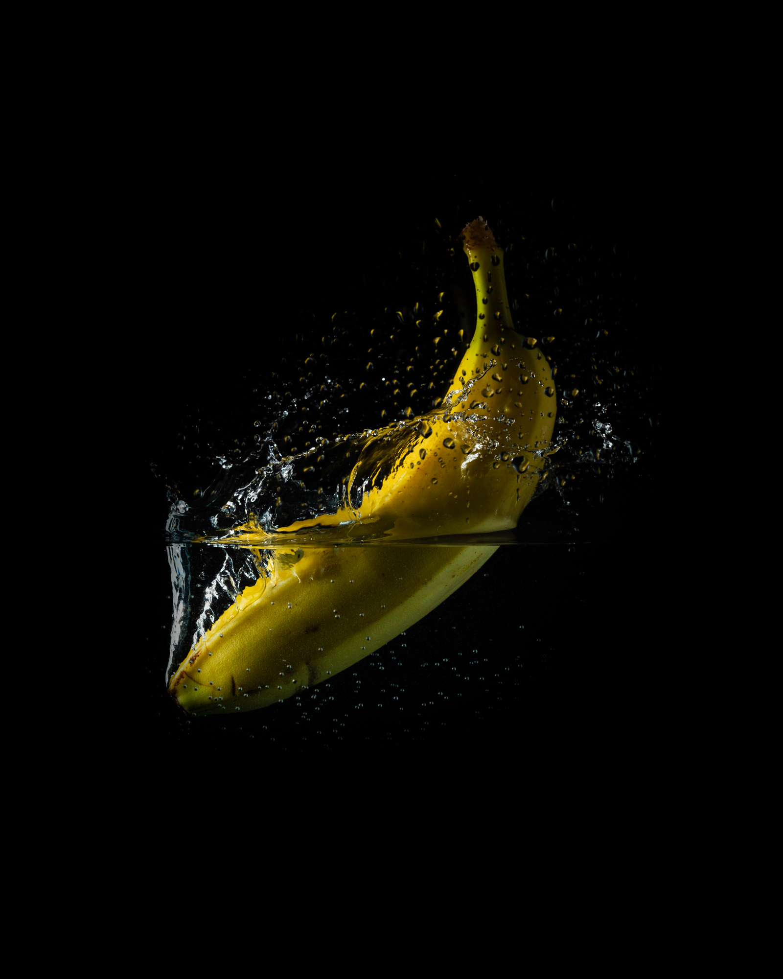 banana in water splash, half submerged, and with air and water bubbles