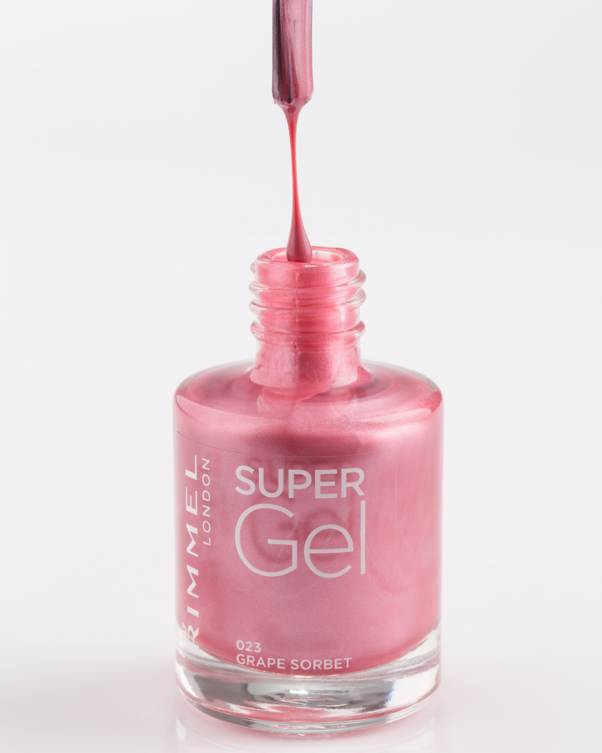 Pink nail polish with a drop above the bottle.