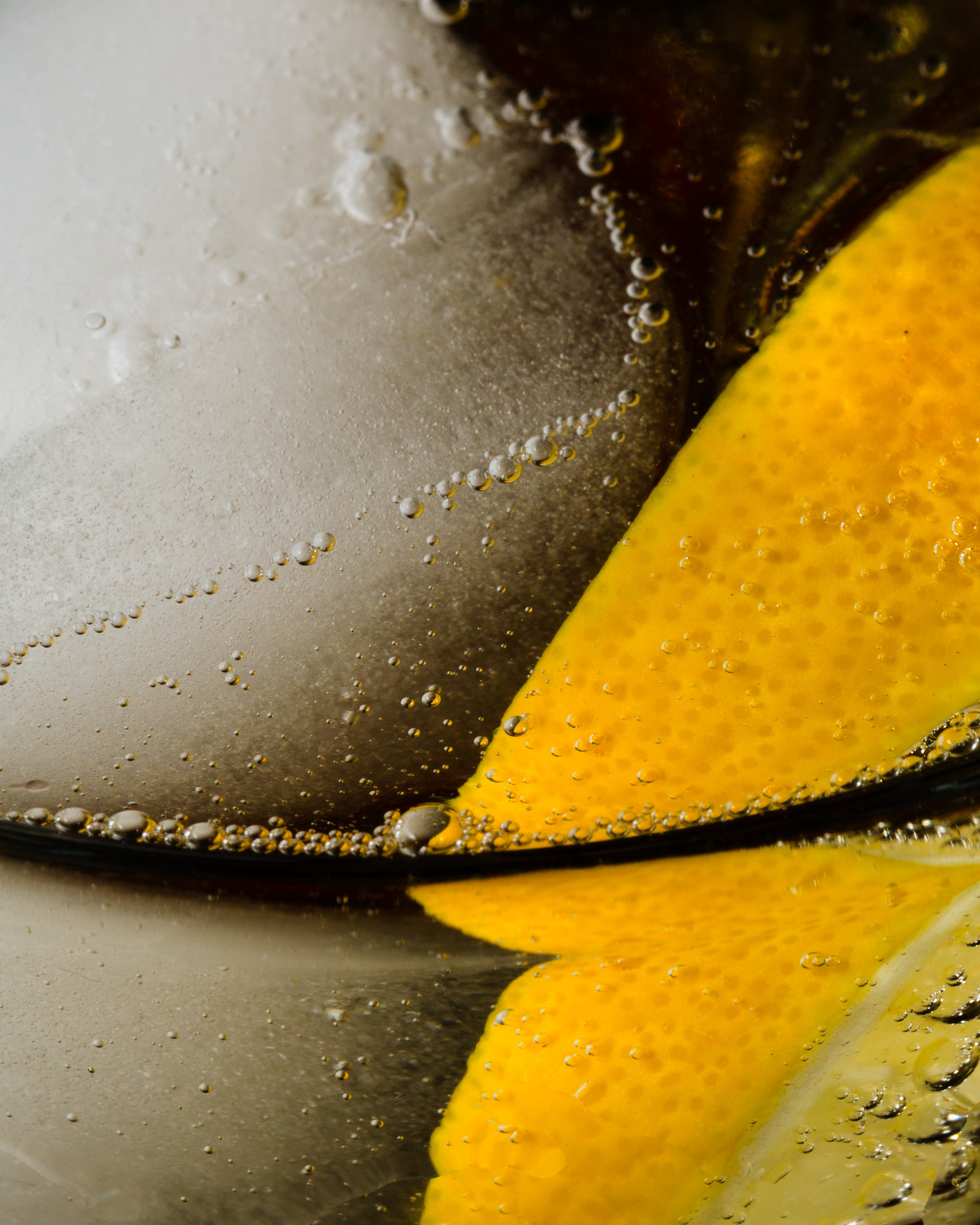 Macro photograph of a drink with a lemon ice cube and bubbles.