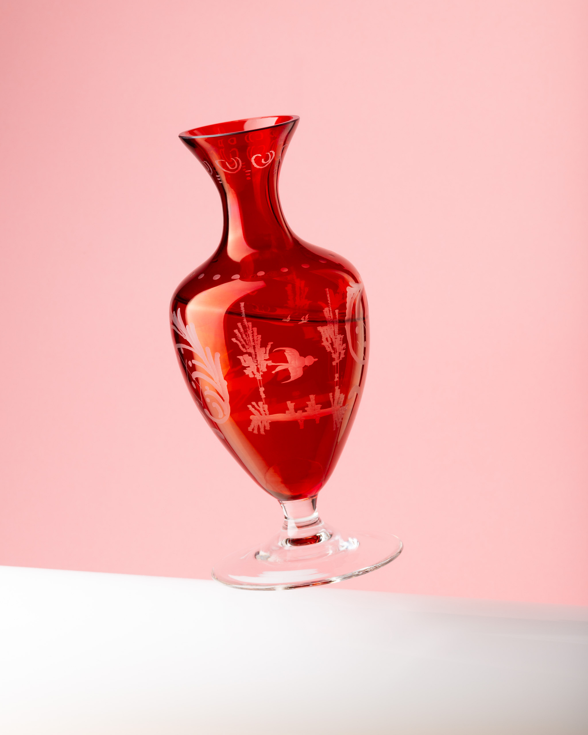 Tilted red vase on a pink background.