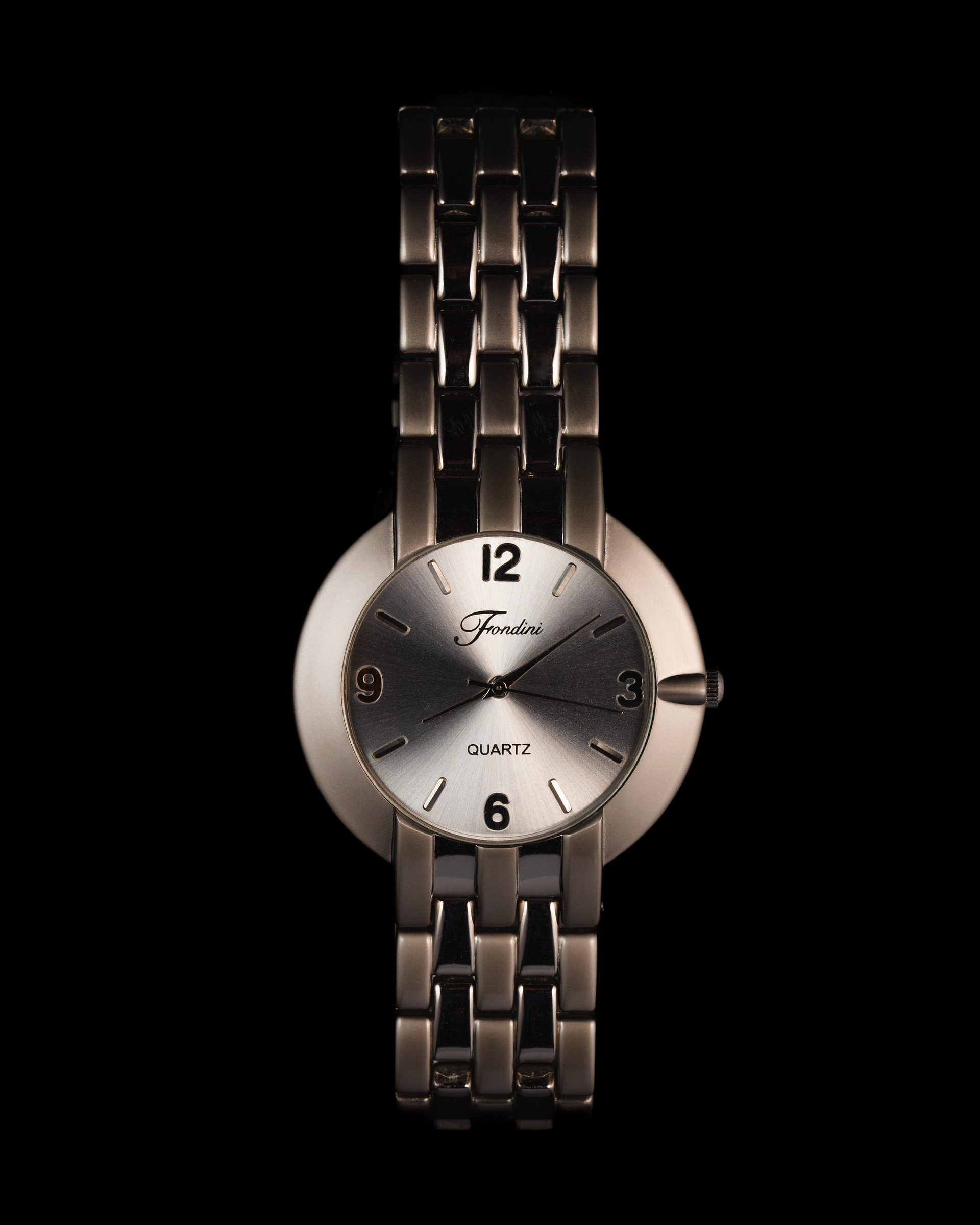 Chrome watch emerging from a dark background.