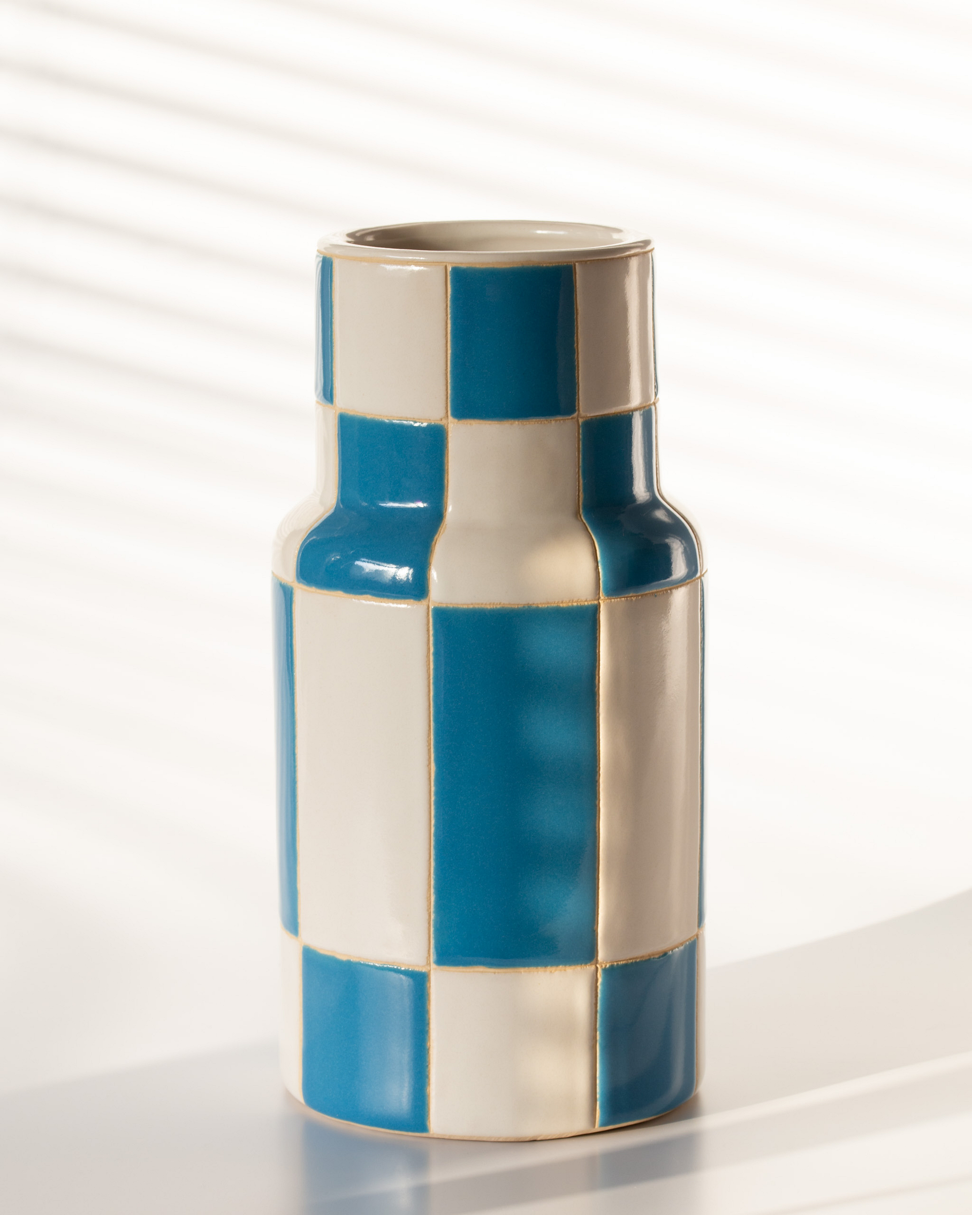 Blue and white checkered vase on a bright background.