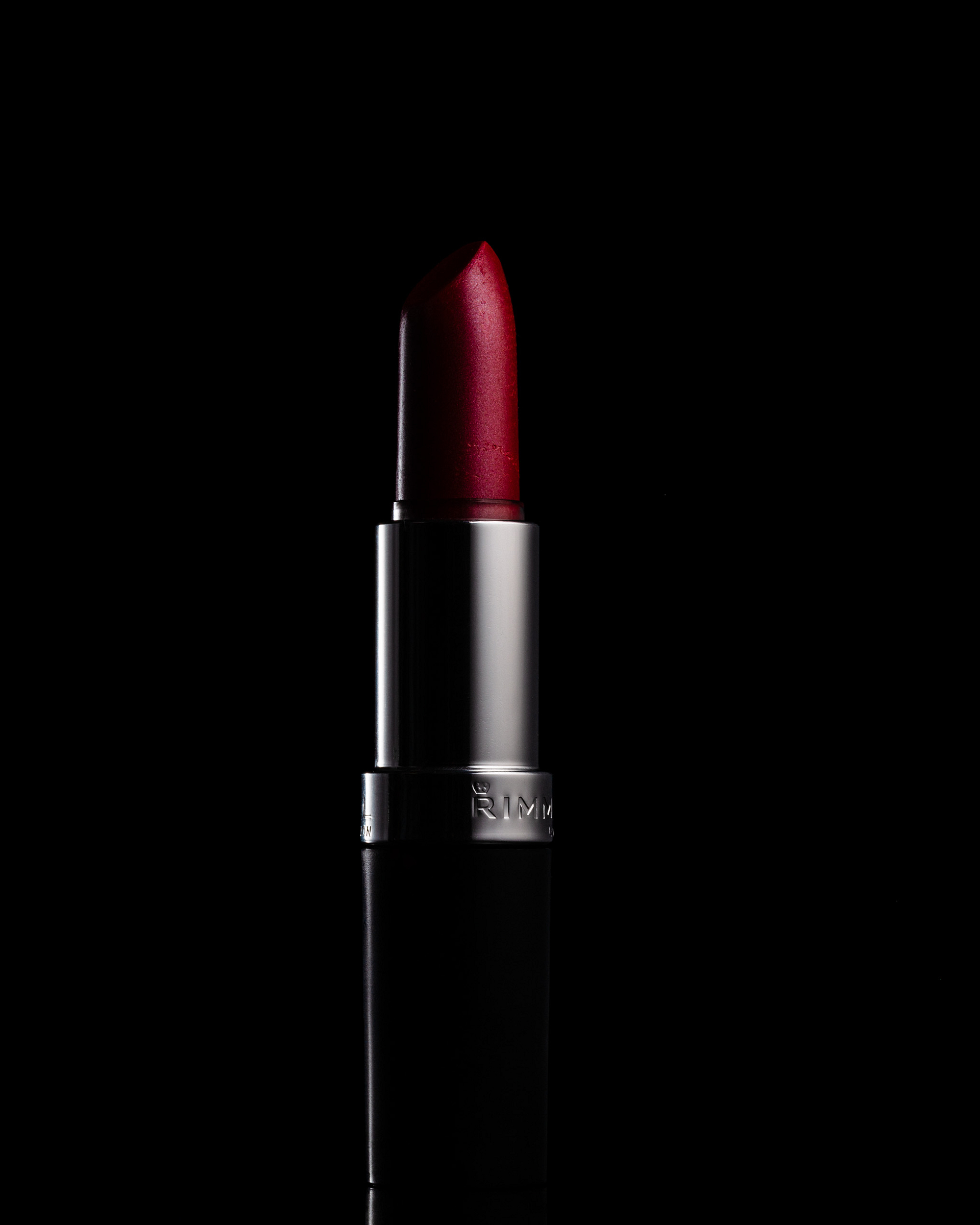 A red lipstick stands upright against a black background.