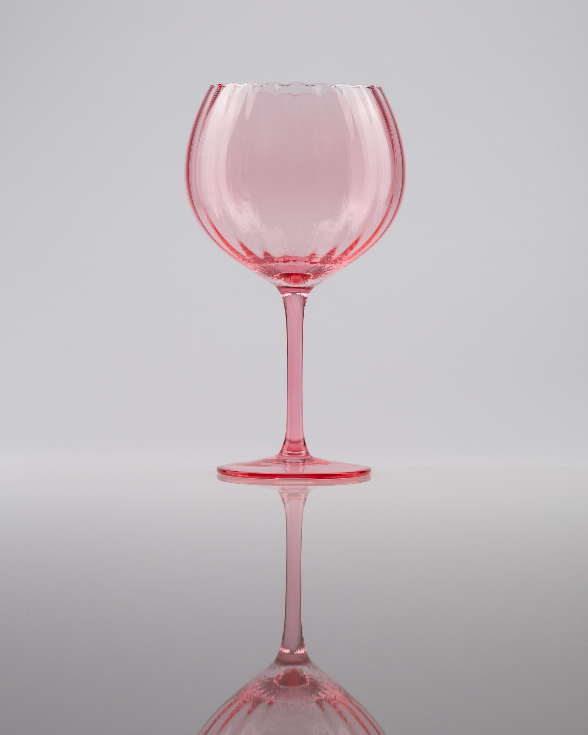 Pink glass with reflection on a light background.