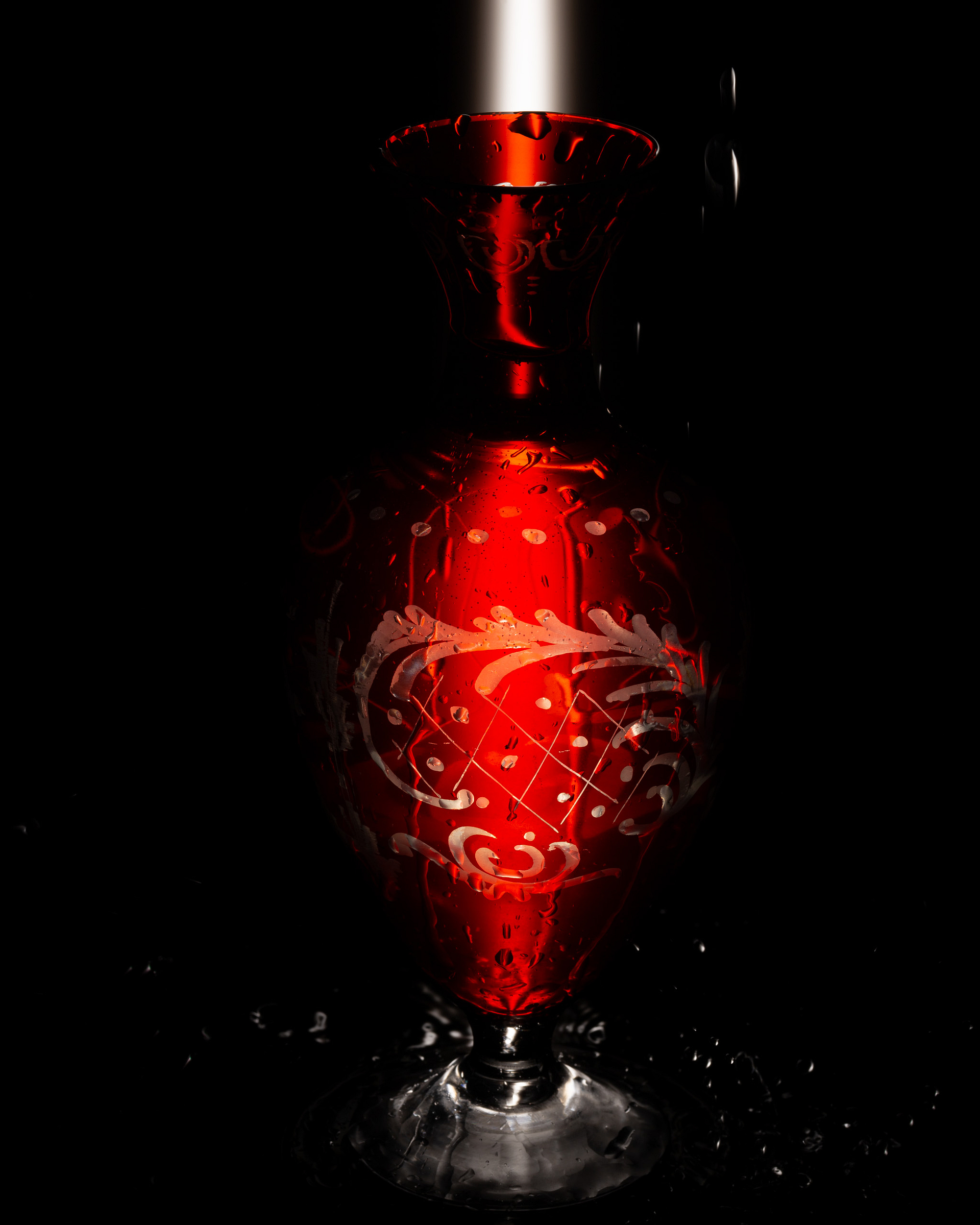 Red vase with reflections and water droplets.