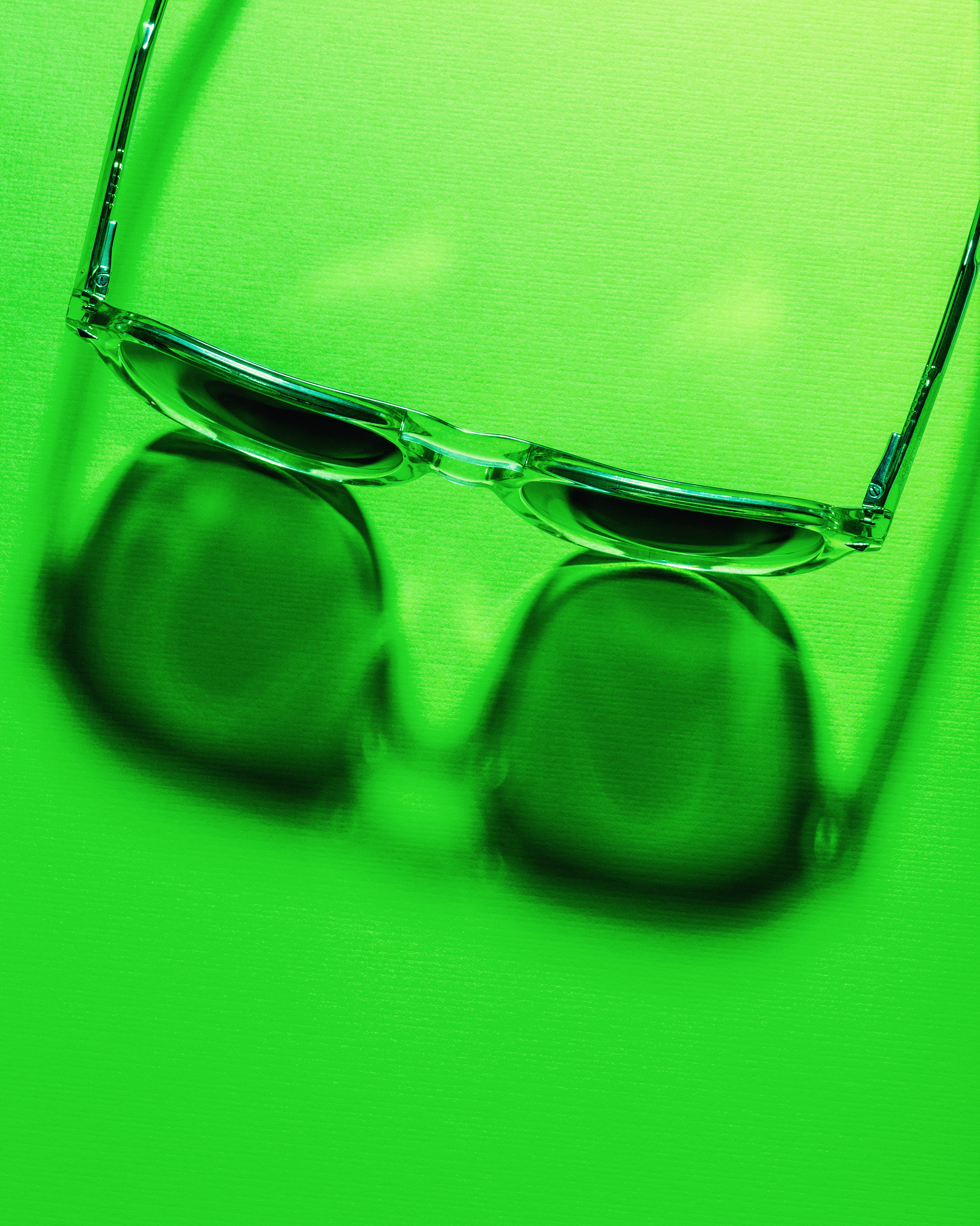 Sunglasses with light and shadow on a green background.