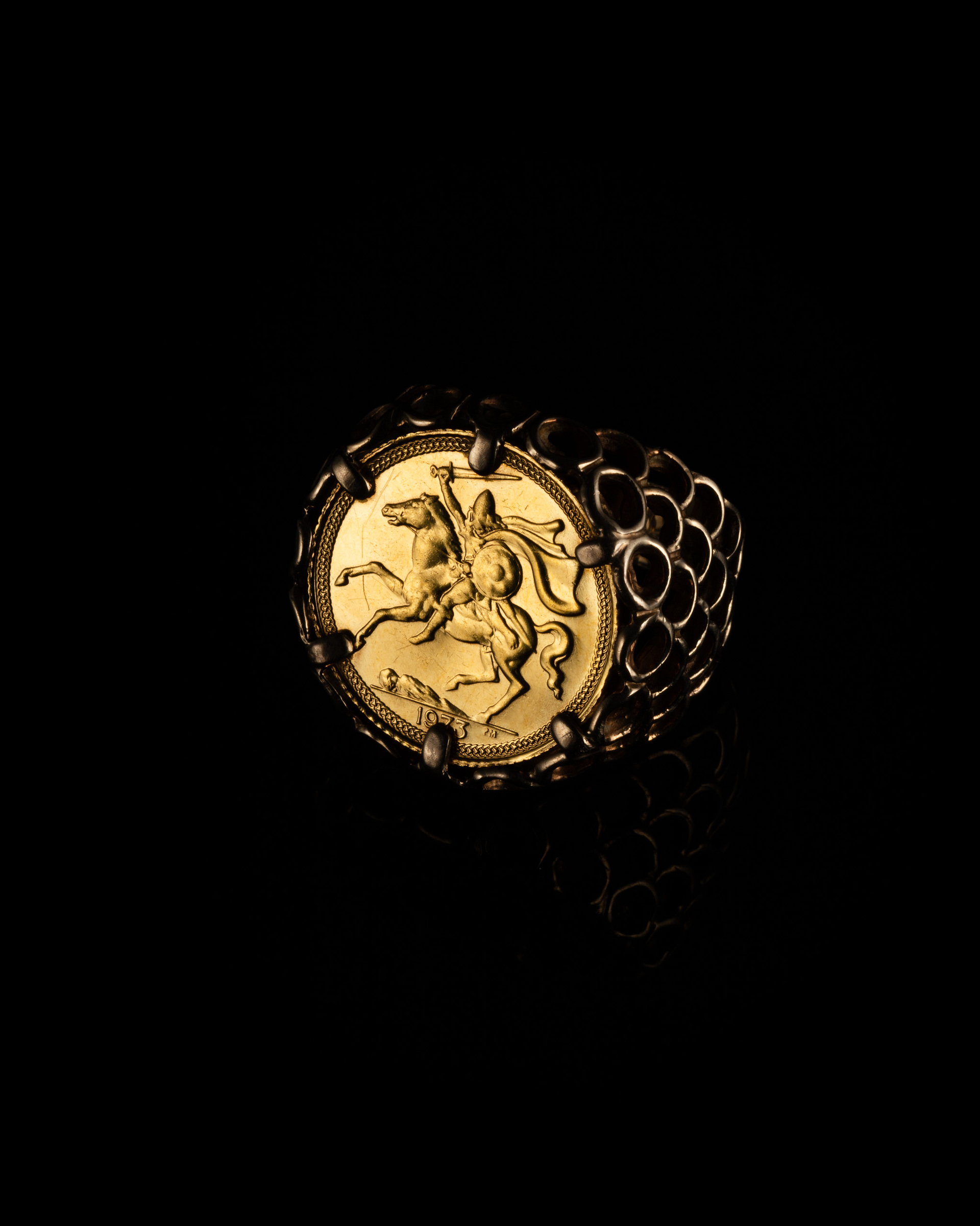 Gold sovereign ring on a black background.