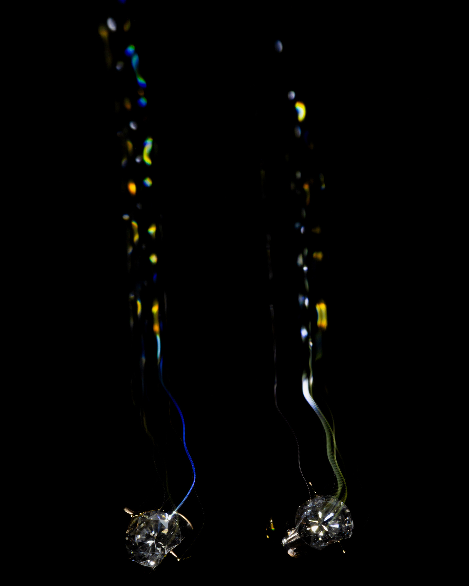 Light-painted diamonds with trails on a dark background.