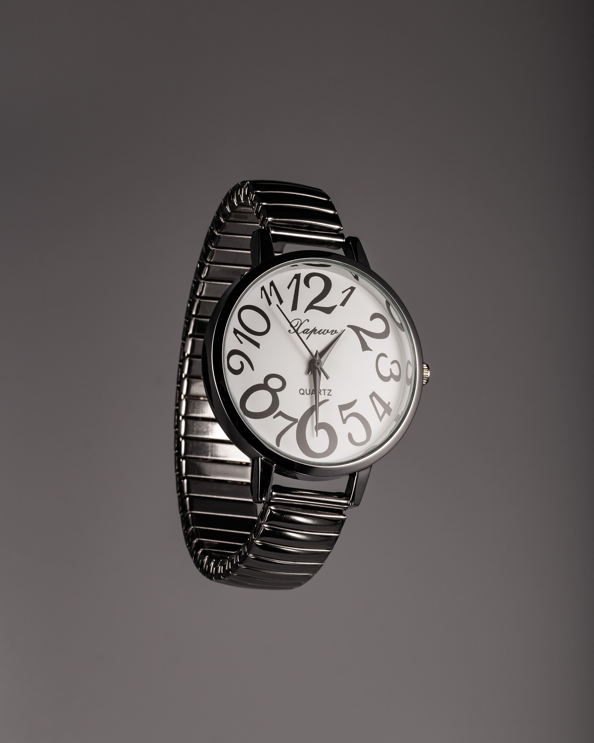 Floating chrome watch with irregular numbers on a dark background.