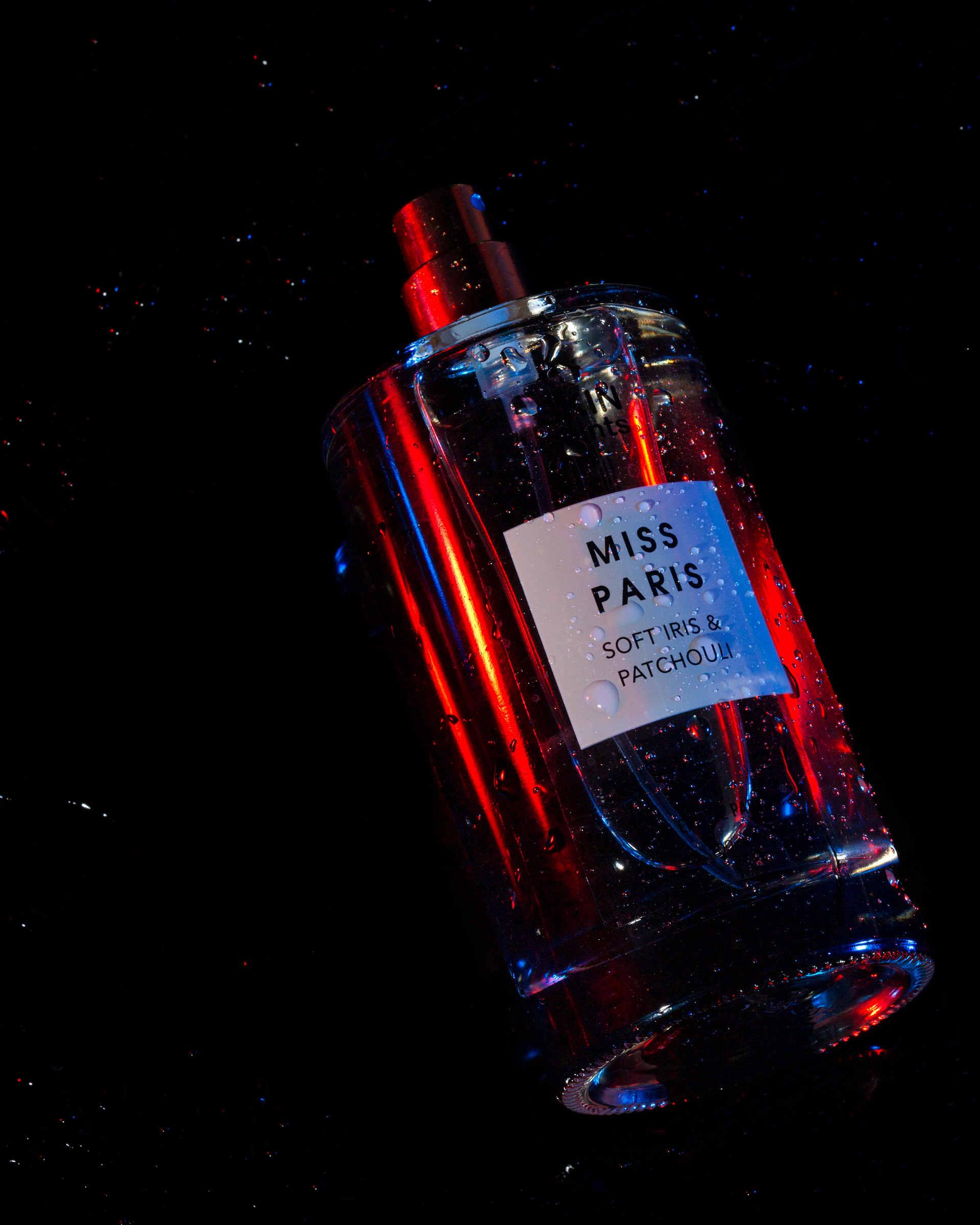 lightpainted perfume bottle with water droplets on a dark background