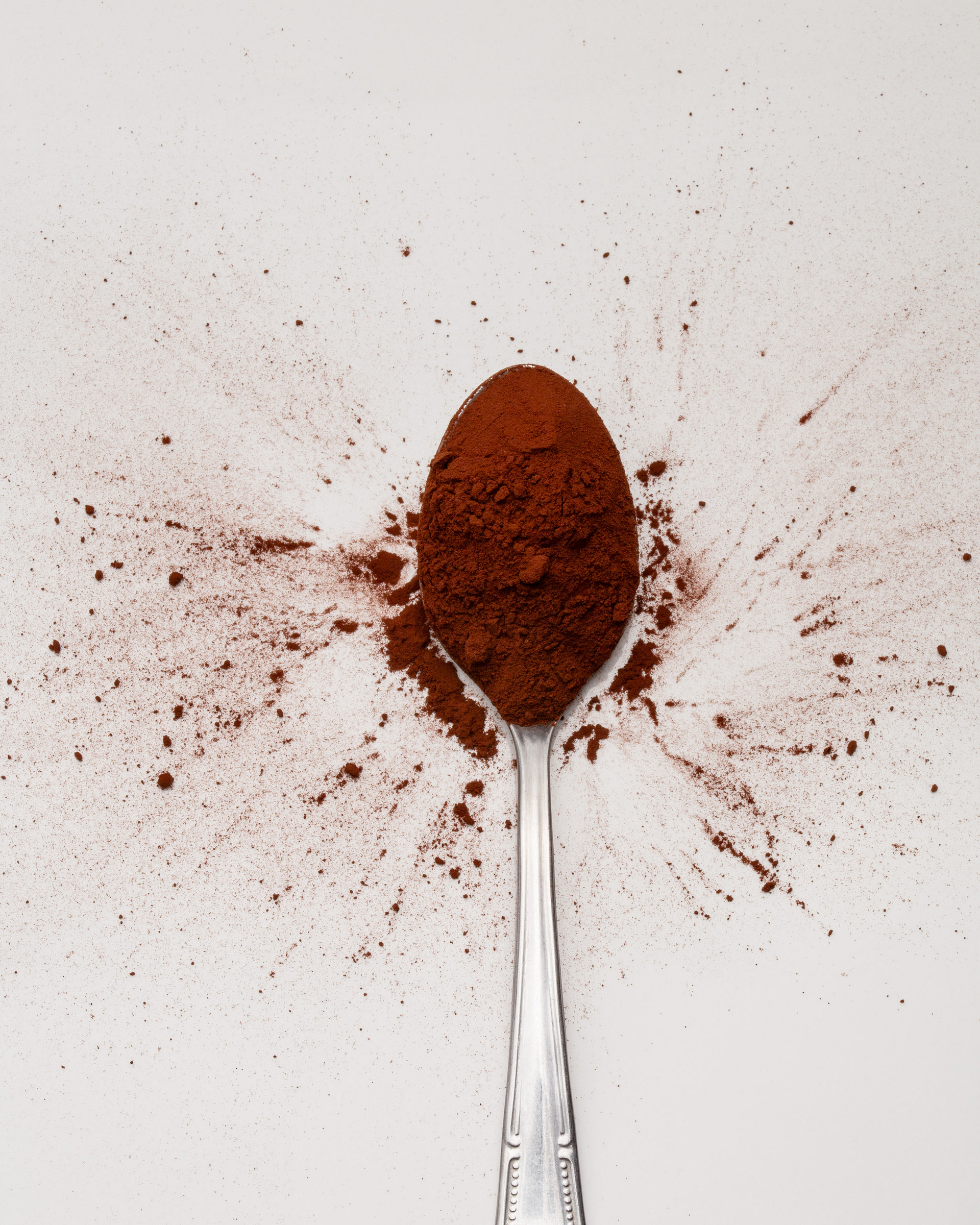 Cocoa powder spreading from a teaspoon.